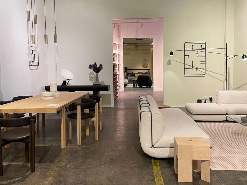 Photo of a dining area on the left and a living room setup on the right, featuring minimalist furniture and lighting.