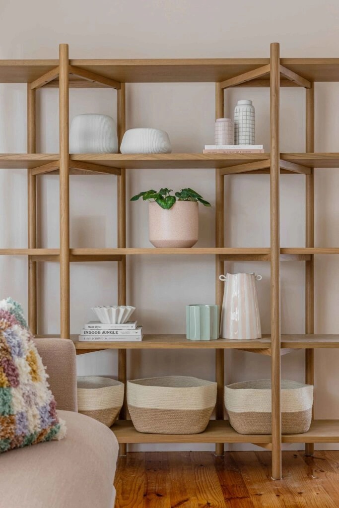 A wooden bookshelf with various decorative objects, including vases, a potted plant, and woven baskets.